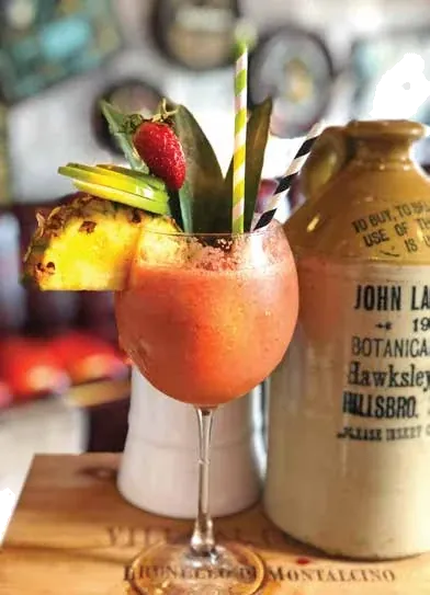 A signature cocktail garnished with pineapple and strawberry