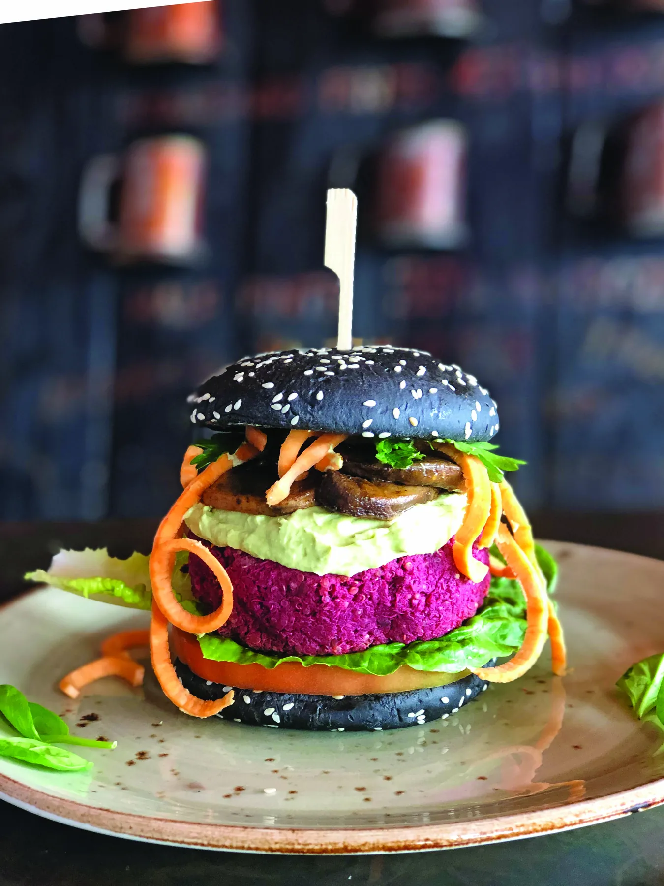 Colourful vegetable burger in a black sesame bun with avocado cream